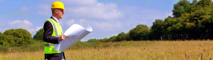 Man wearing a hard hat, walking through a field