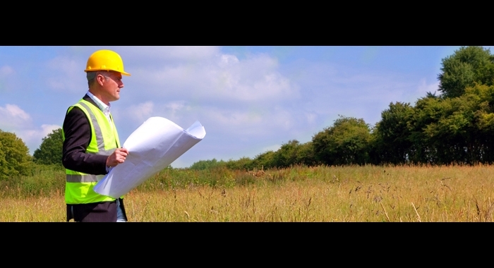 Man wearing a hard hat, walking through a field